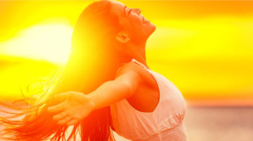 Happy woman feeling free with open arms in sunshine at beach sunset. Freedom and carefree enjoyment girl enjoying life. Beautiful woman in white dress for success, health, hope and faith concept.